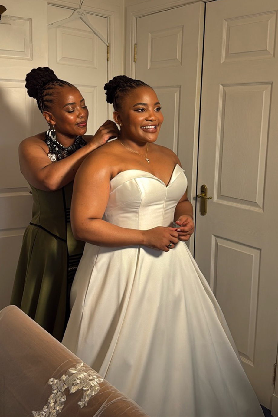 Radiant bride has her necklace put on by member of her bridal party